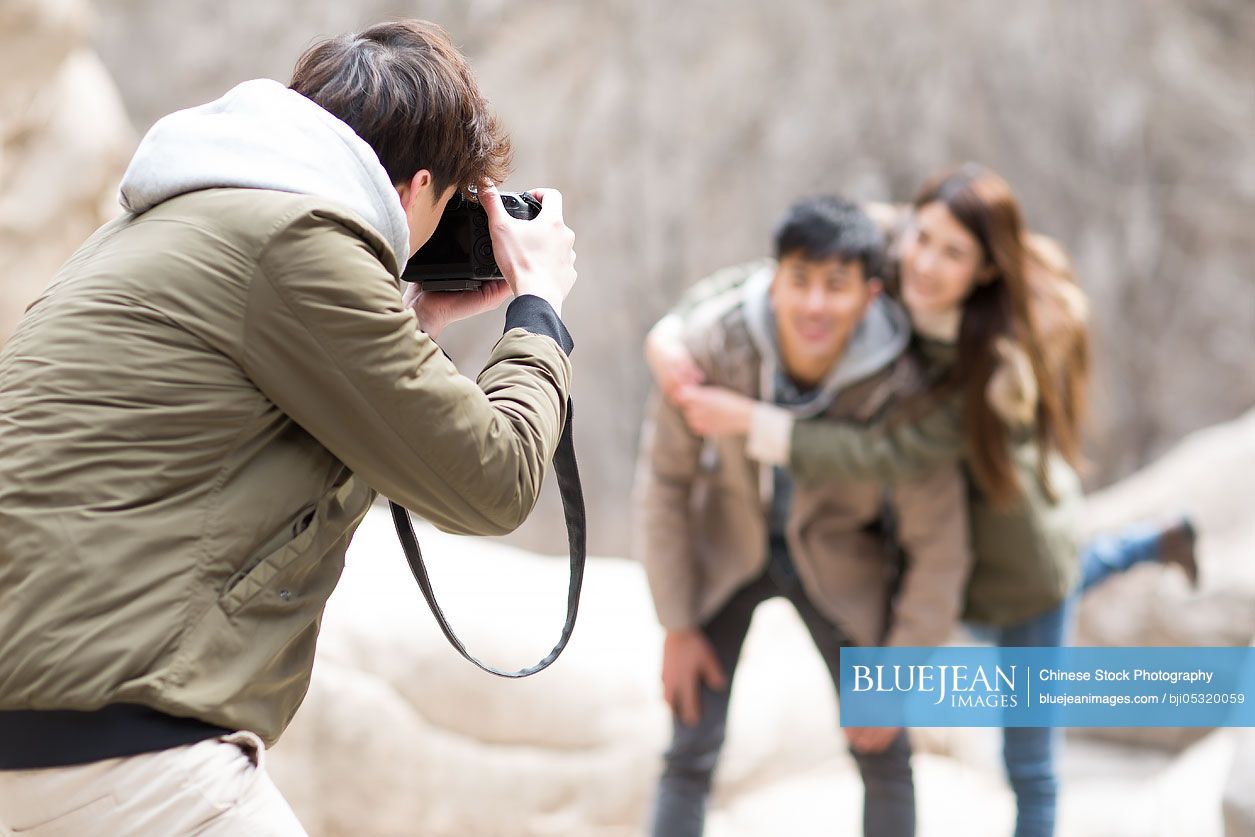 Happy young Chinese friends taking pictures outdoors in winter