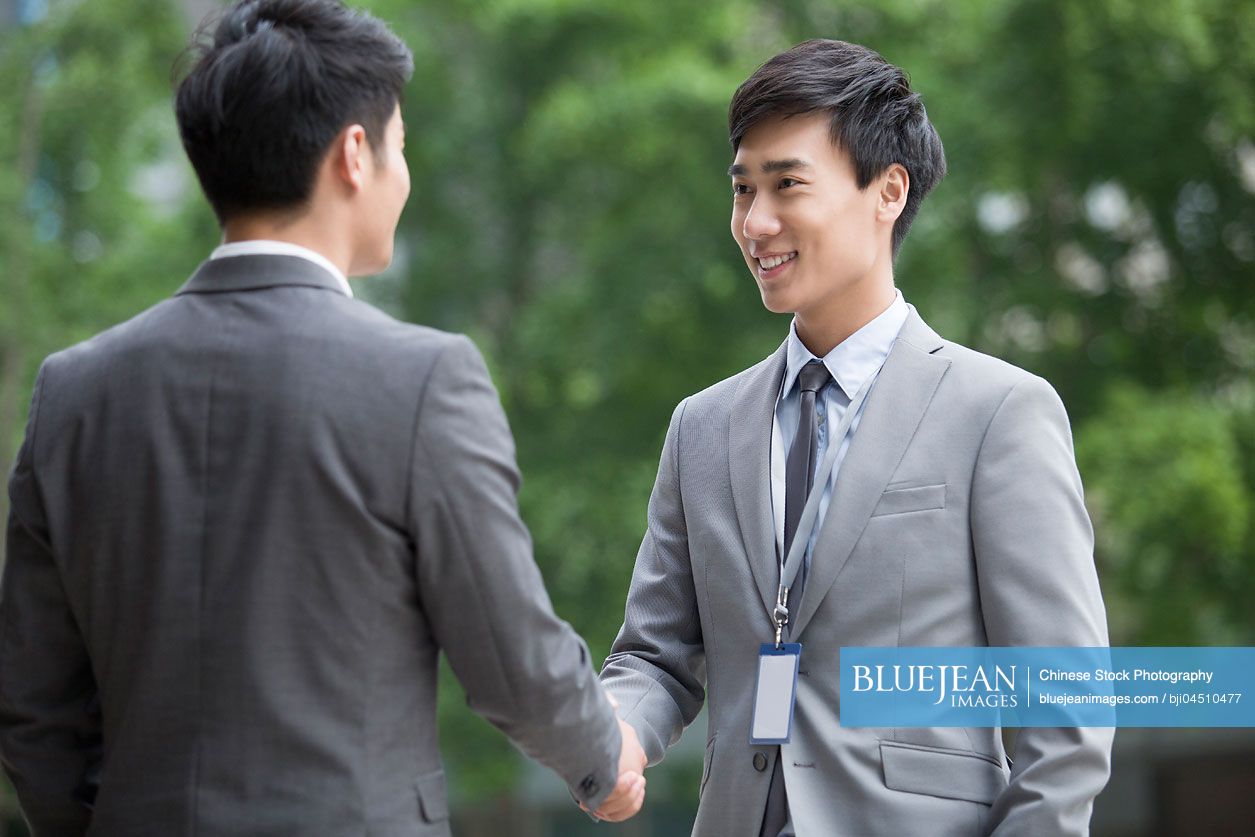 Young Chinese business person shaking hands outdoors