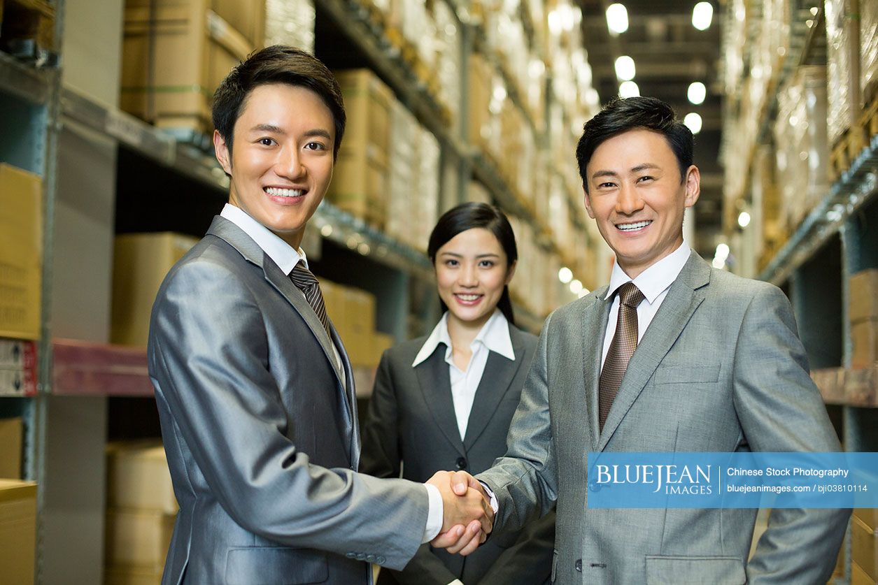 Chinese business people shaking hands in warehouse