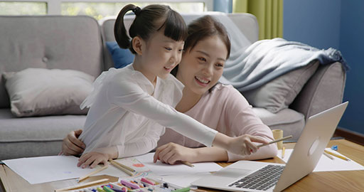 Little girl drawing with her mom by her side