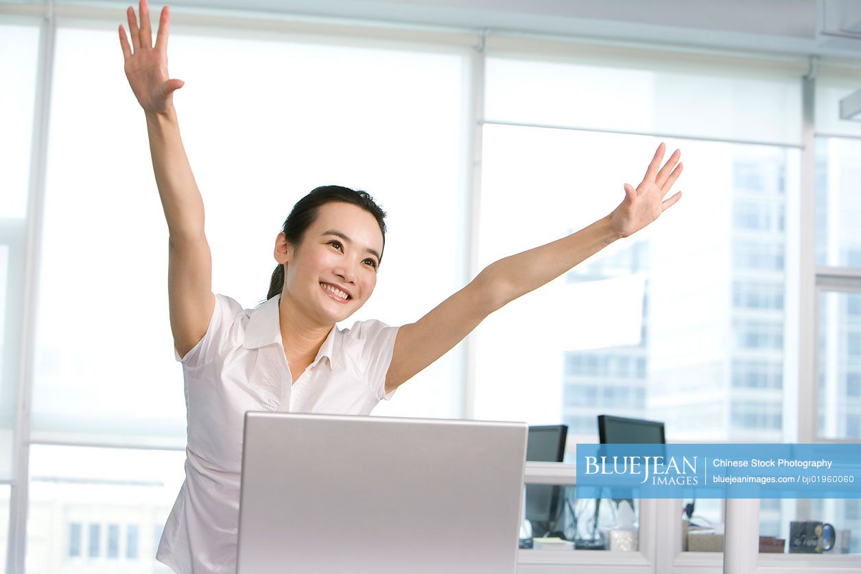 Happy Chinese office worker at her desk