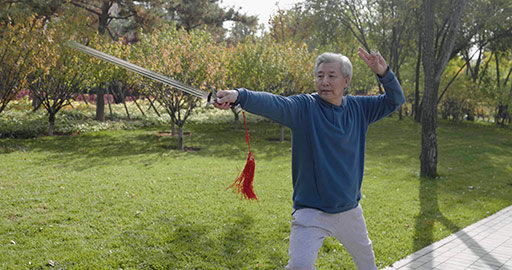 Cheerful senior Chinese man practicing sword in the park,4K