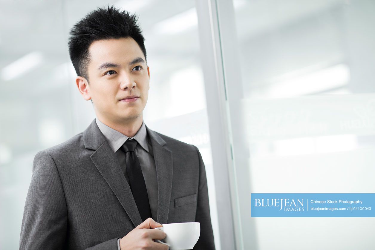 Happy Chinese businessman having coffee