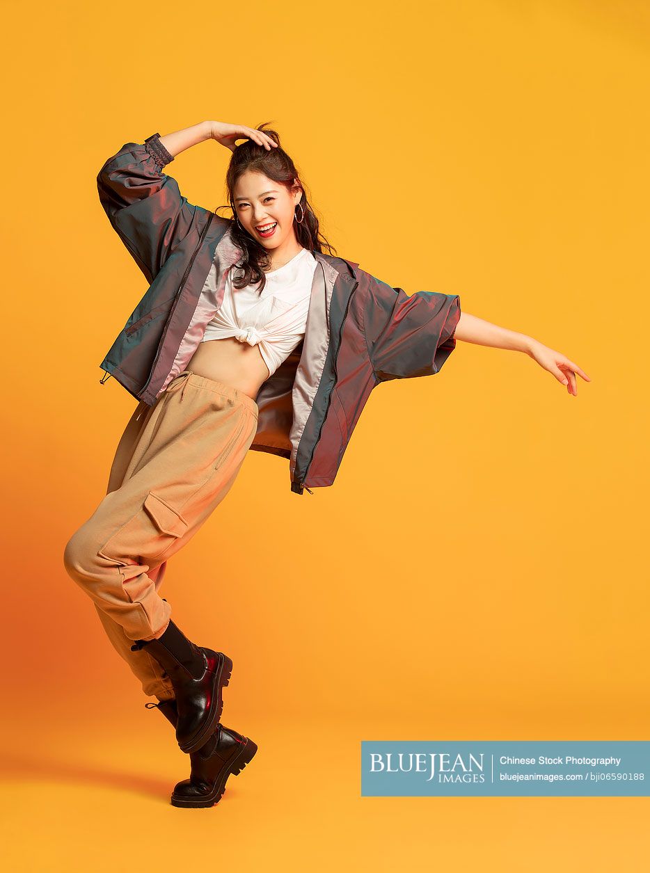Studio shot of fashionable young Chinese woman dancing