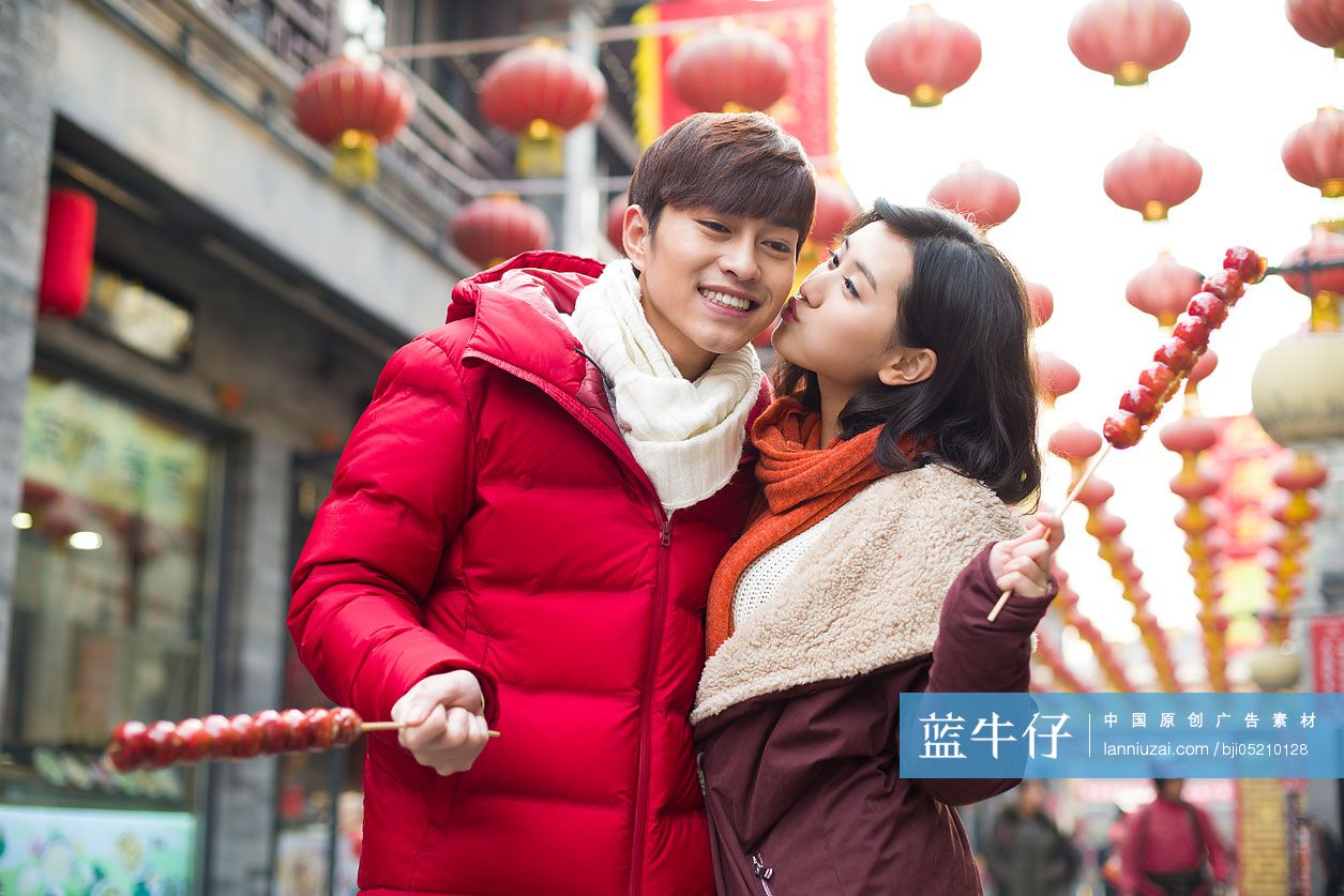 年轻情侣逛街吃冰糖葫芦