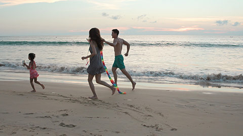 快乐的年轻家庭在沙滩放风筝