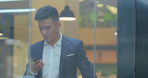 Confident Chinese businessman using smartphone in office,4K