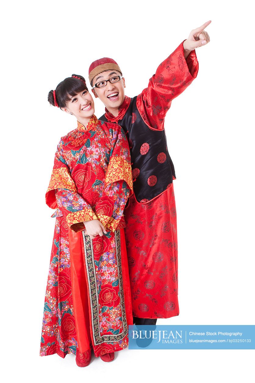 Happy Chinese couple in traditional clothing pointing away