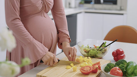 Young pregnant Chinese woman cooking food