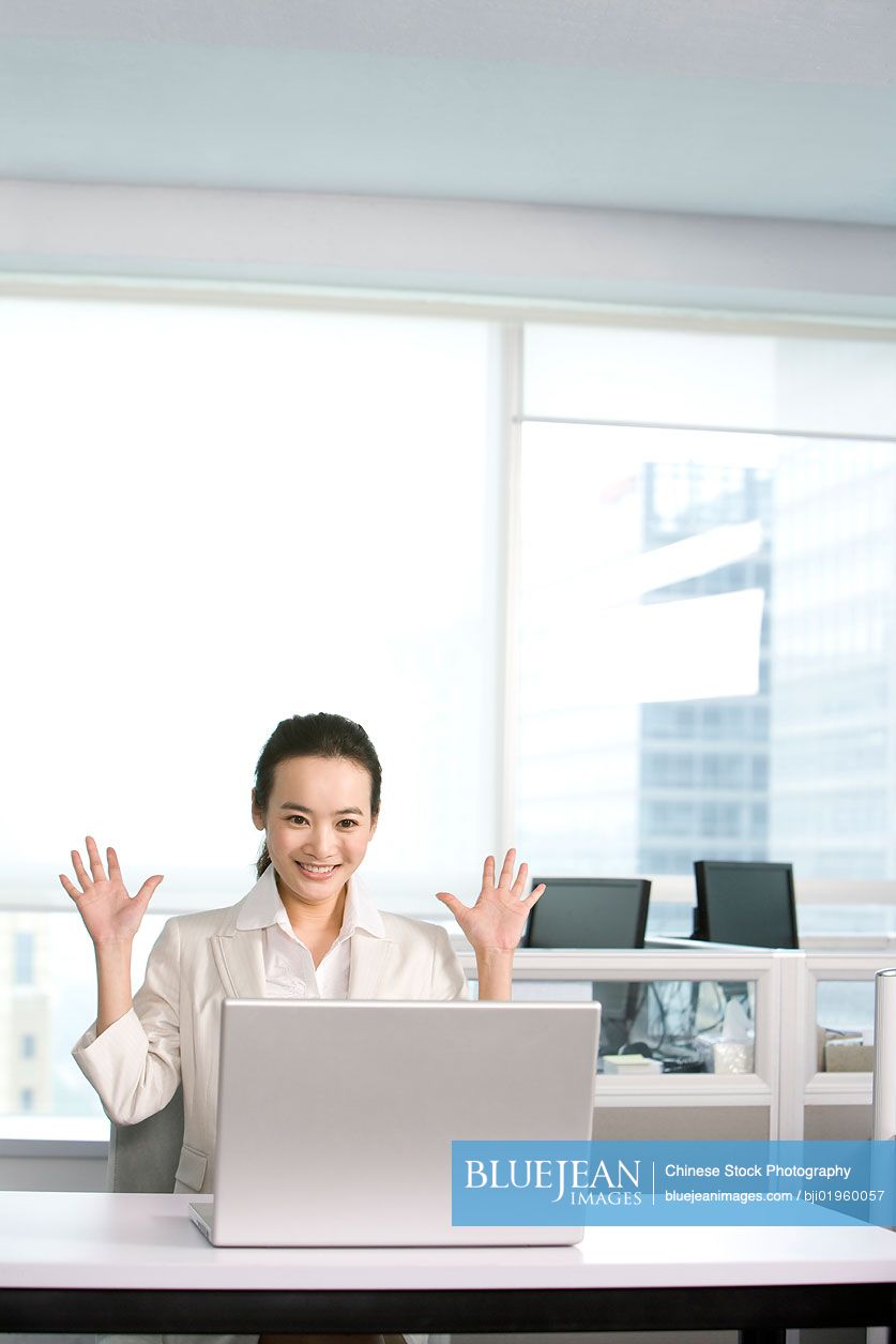 Happy Chinese office worker at her desk