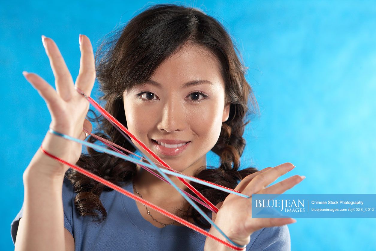 Young Chinese women making cats cradle