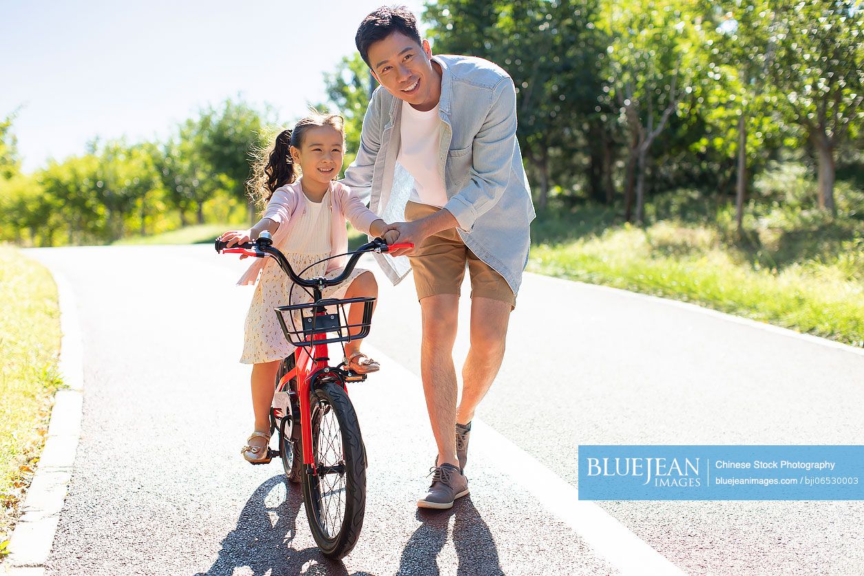 Chinese father teaching daughter to ride bike