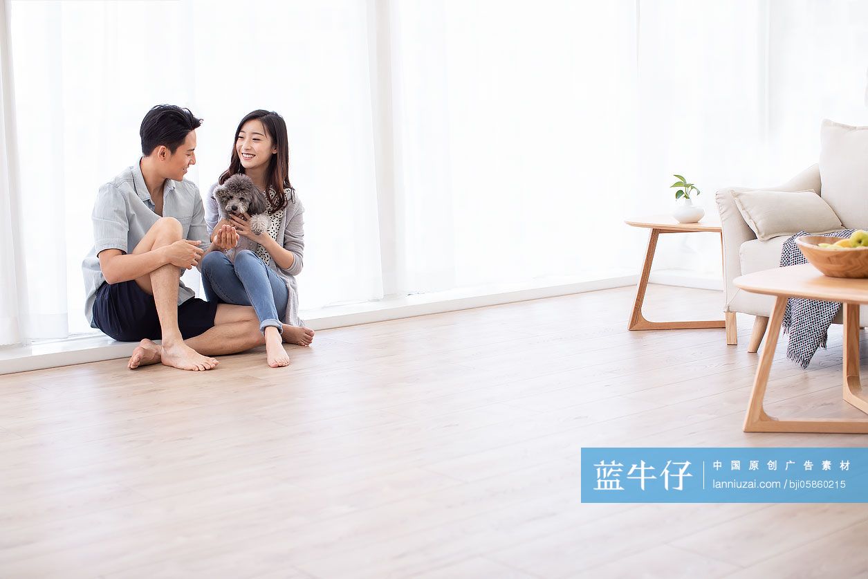 快乐的年轻情侣在客厅和狗玩耍