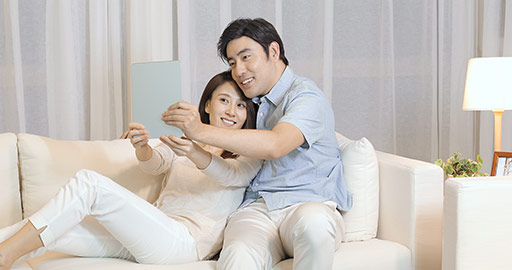 Happy young Chinese couple using digital tablet in living room,4K