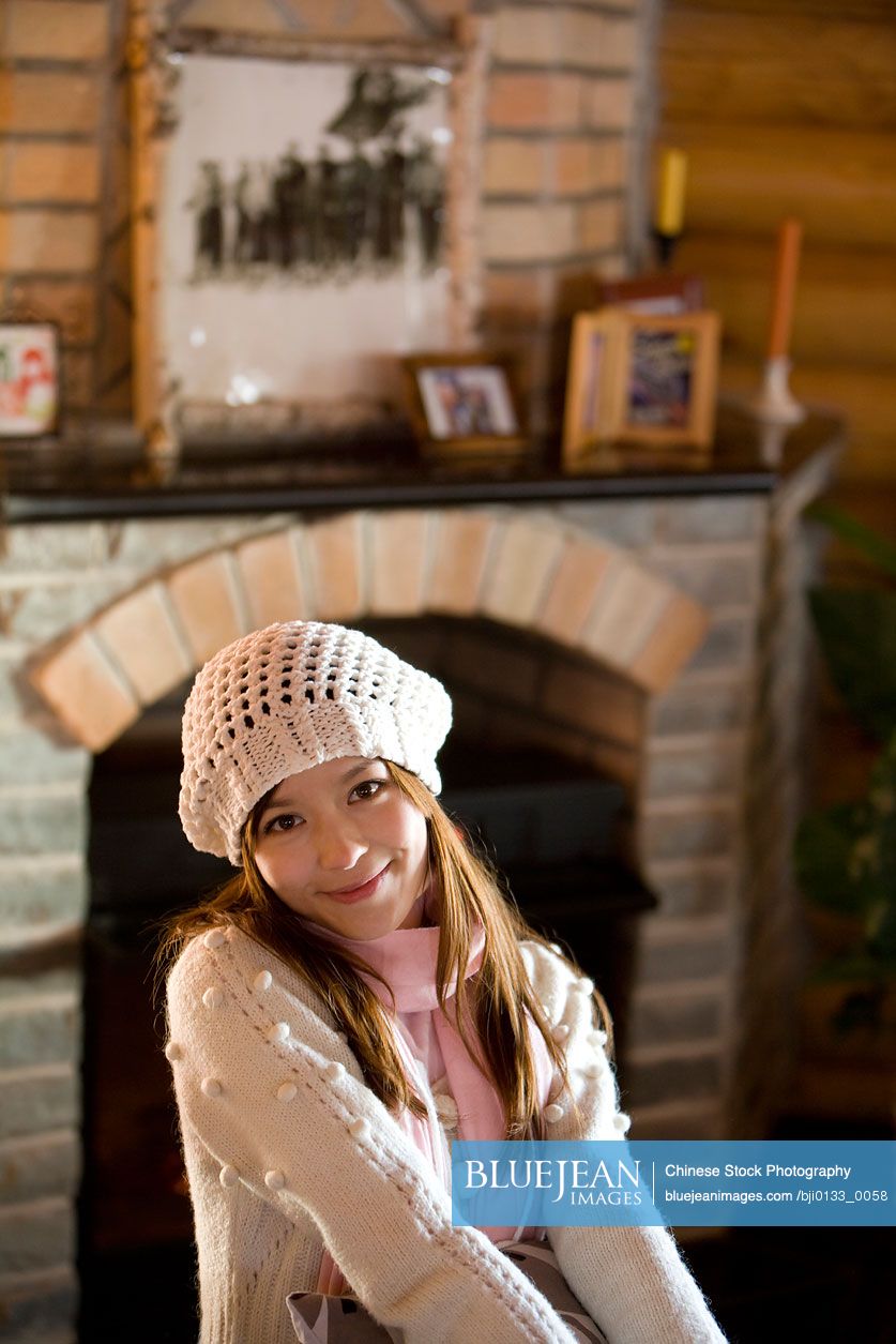 Young Chinese woman smiling in front of a fireplace