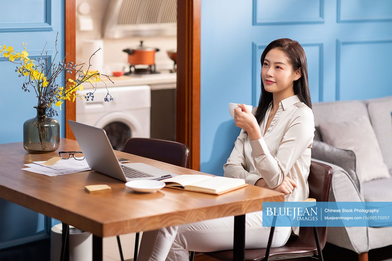 Young Chinese woman drinking coffee at home