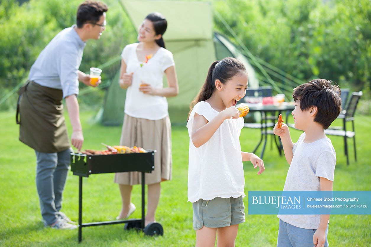 Young Chinese family barbecuing outdoors