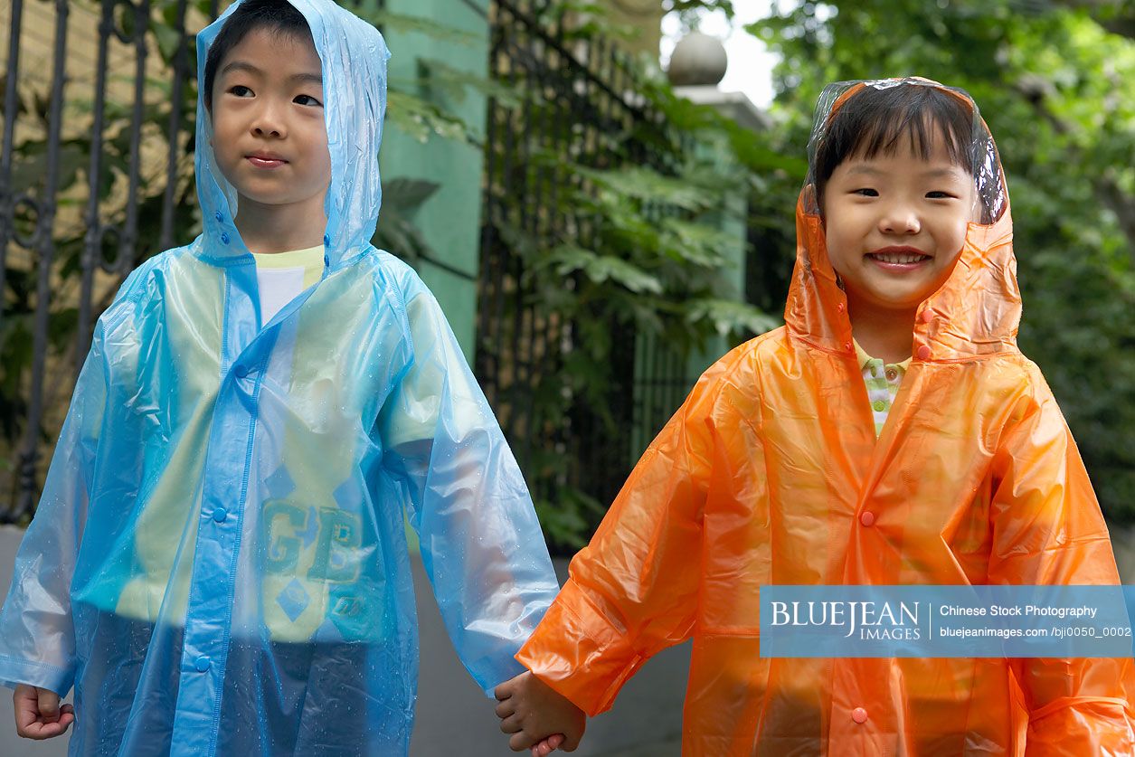 Chinese children wearing raincoats holding hands