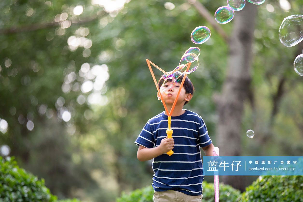 小男孩在草地上吹泡泡