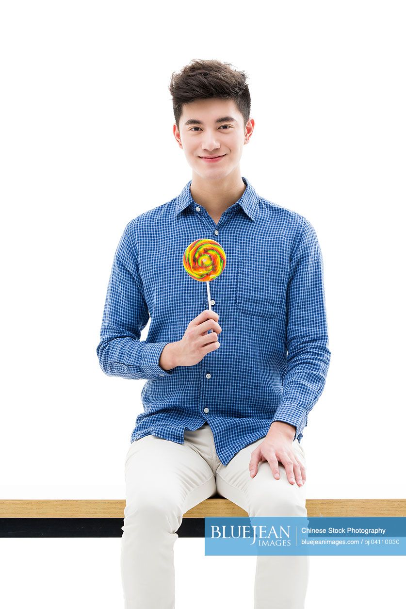 Young Chinese man holding a lollipop