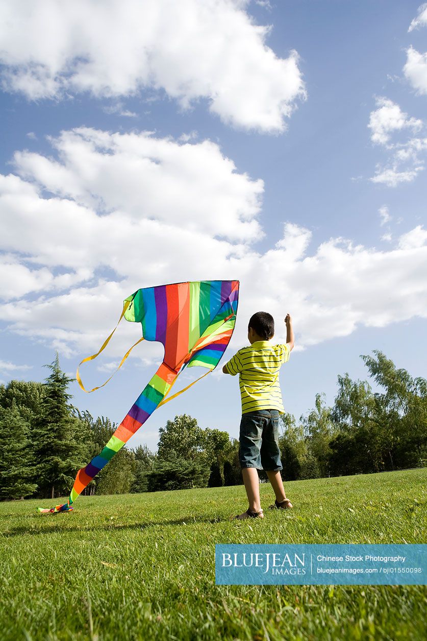 Young Chinese boy running with kite outdoors