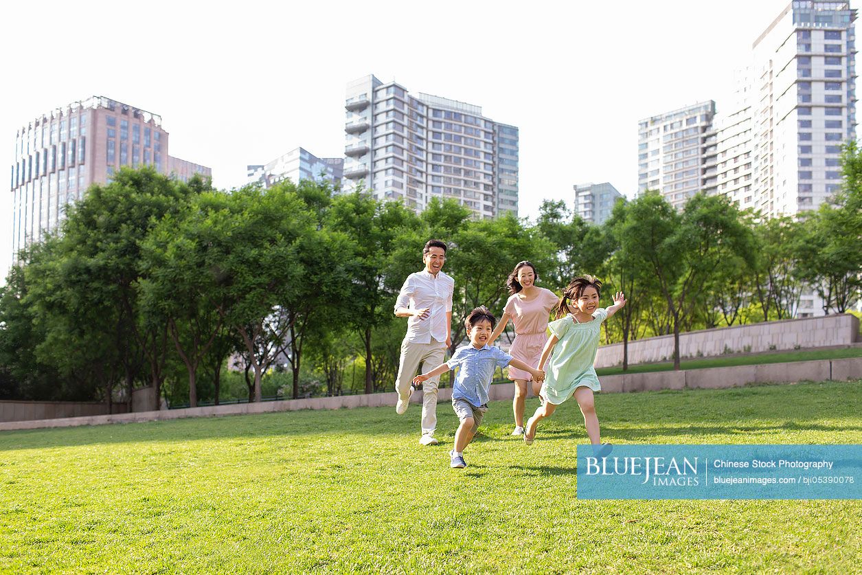 Happy young Chinese family playing in park