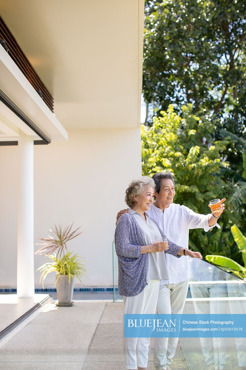 Happy senior Chinese couple relaxing on balcony