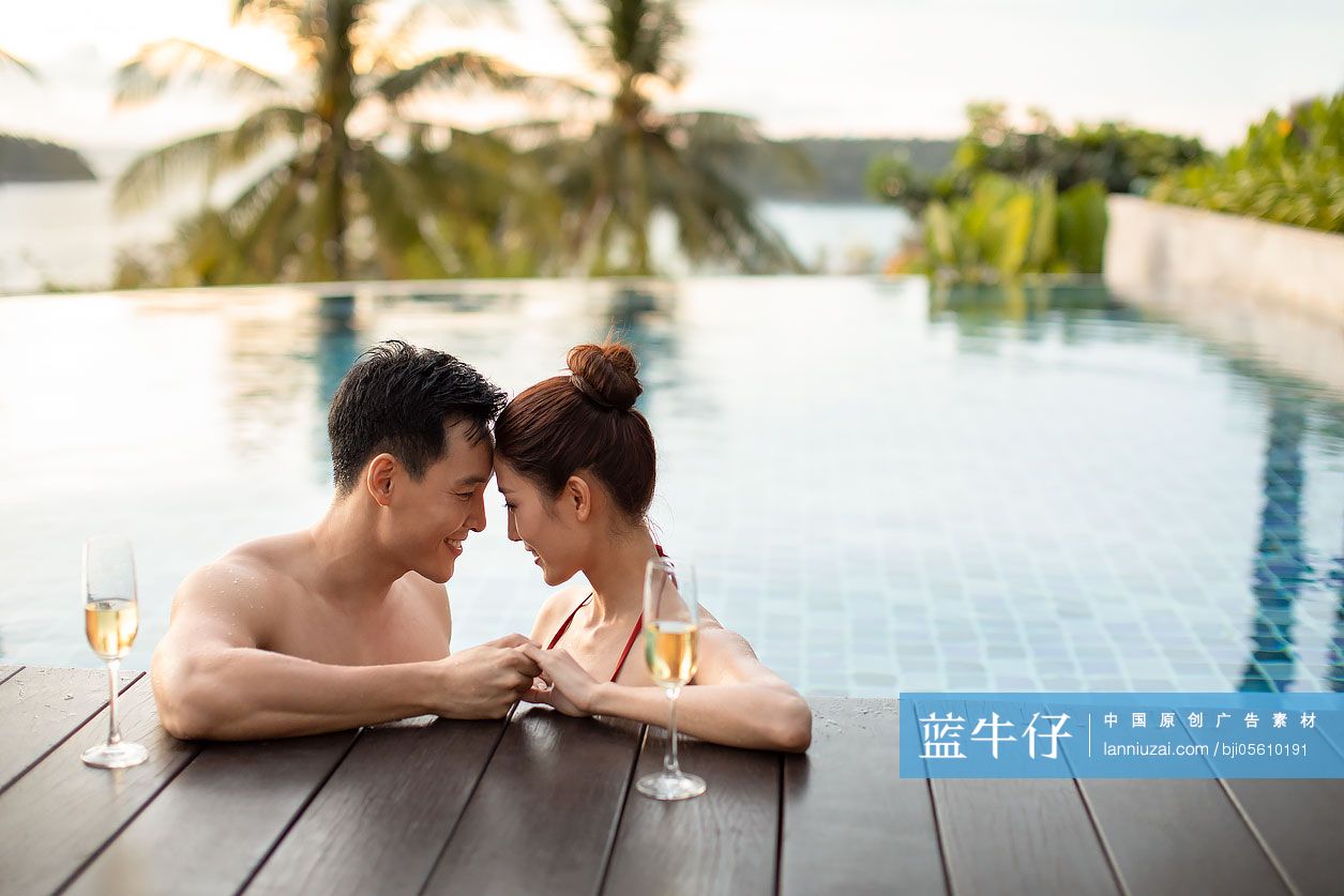 快乐的年轻情侣在泳池边喝香槟