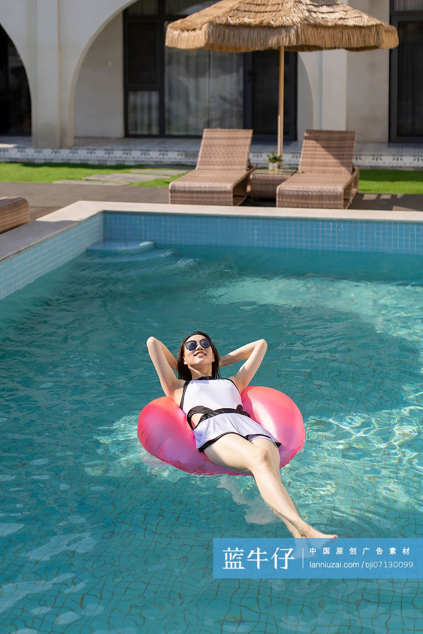 快乐的年轻女子在泳池里晒日光浴