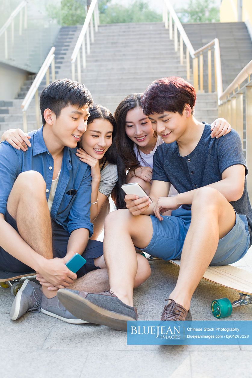 Young Chinese friends looking at a smart phone