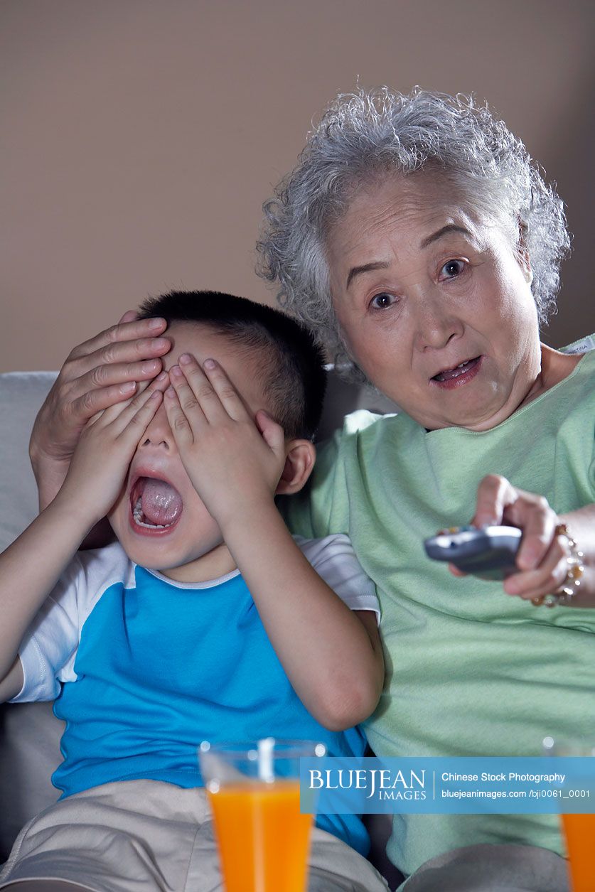 Elderly Chinese Woman And Young Child Watching Television