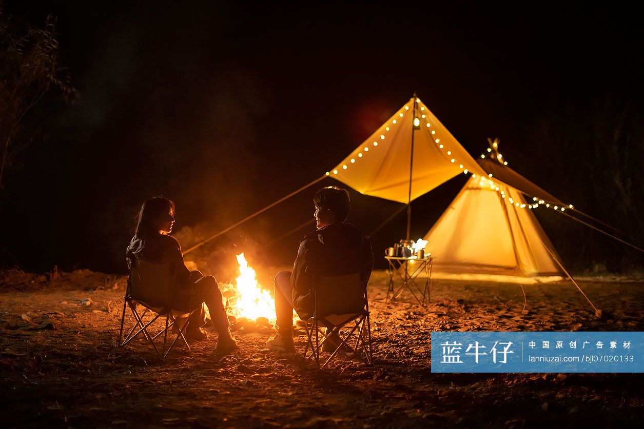 年轻情侣晚上在户外露营烤火