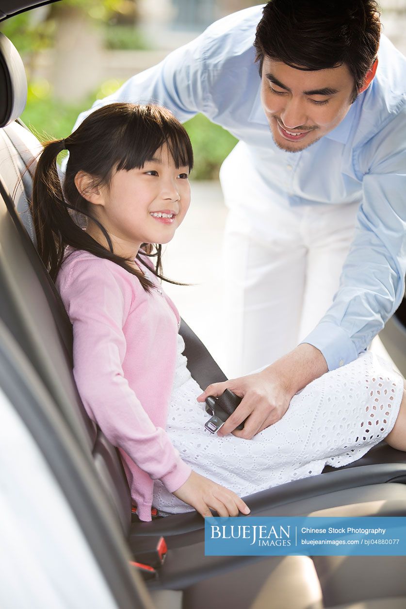 Chinese father fastening seat belt for daughter