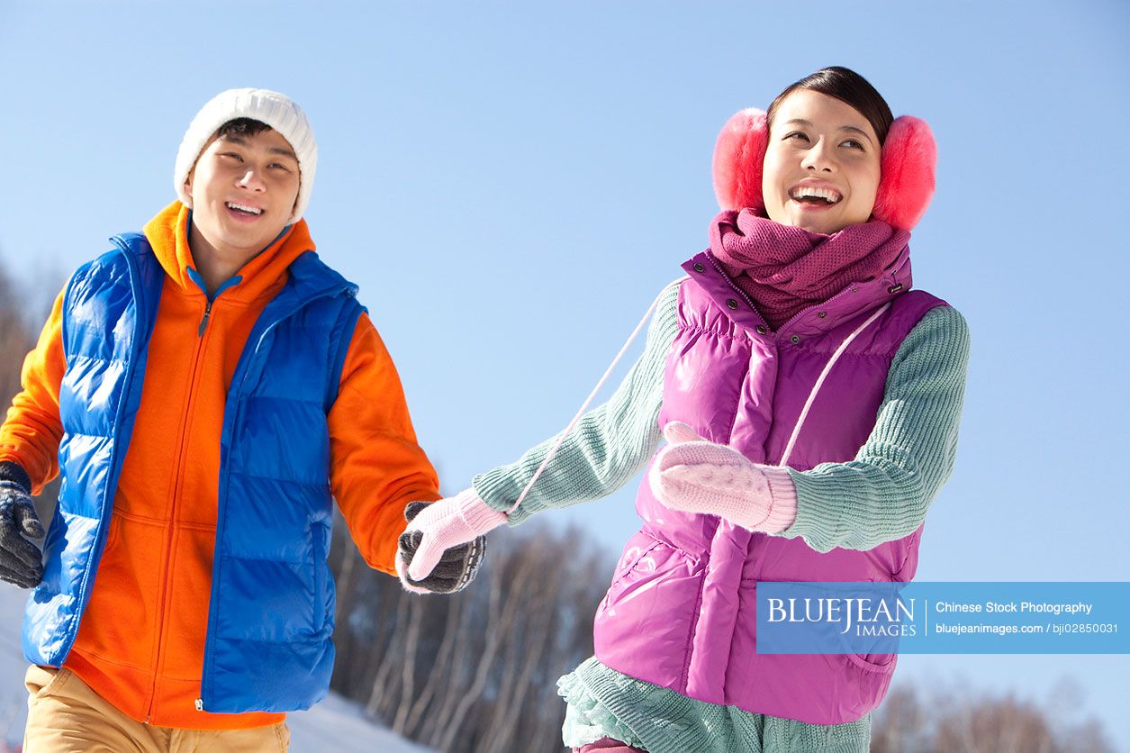 Happy young Chinese couple in ski resort