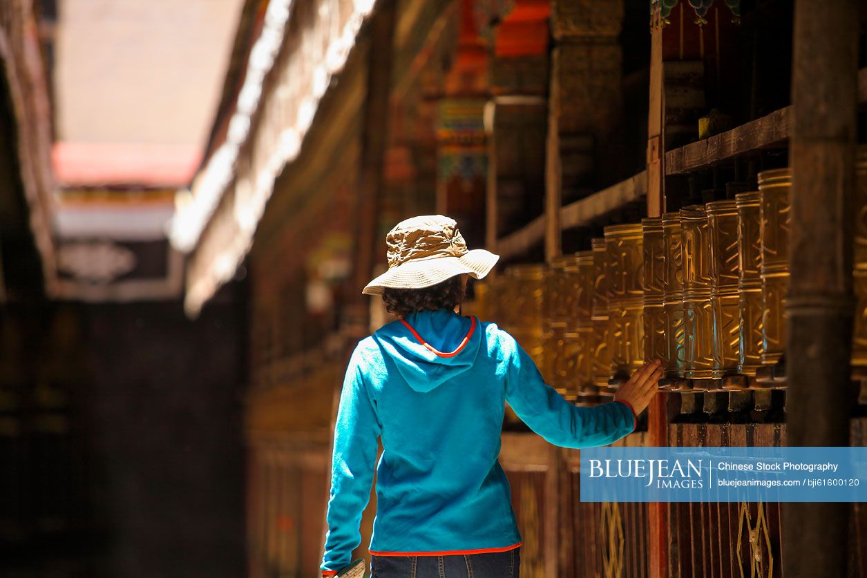 Chinese tourist touching prayer wheel in Jokhang Temple