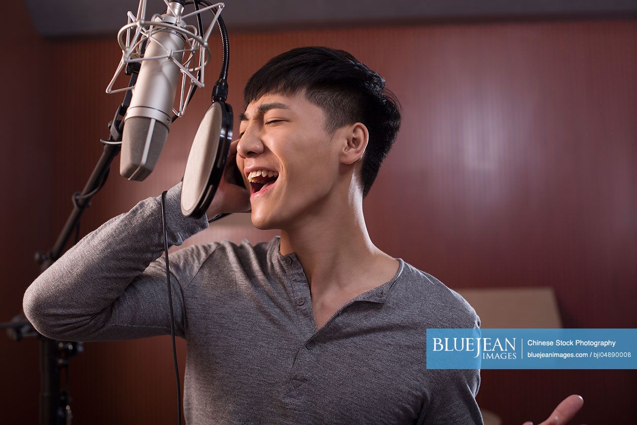 Young Chinese man singing in recording studio