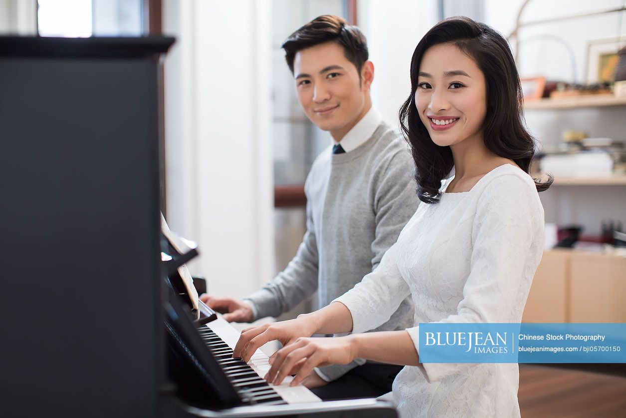Noble young Chinese couple playing the piano together 