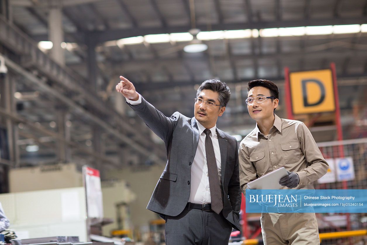 Chinese businessman and engineer talking in the factory