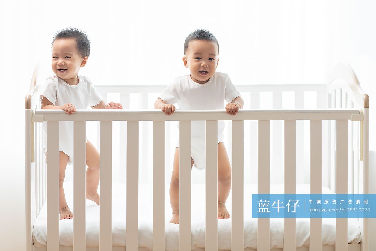 可爱的龙凤胎宝宝在婴儿床里玩耍