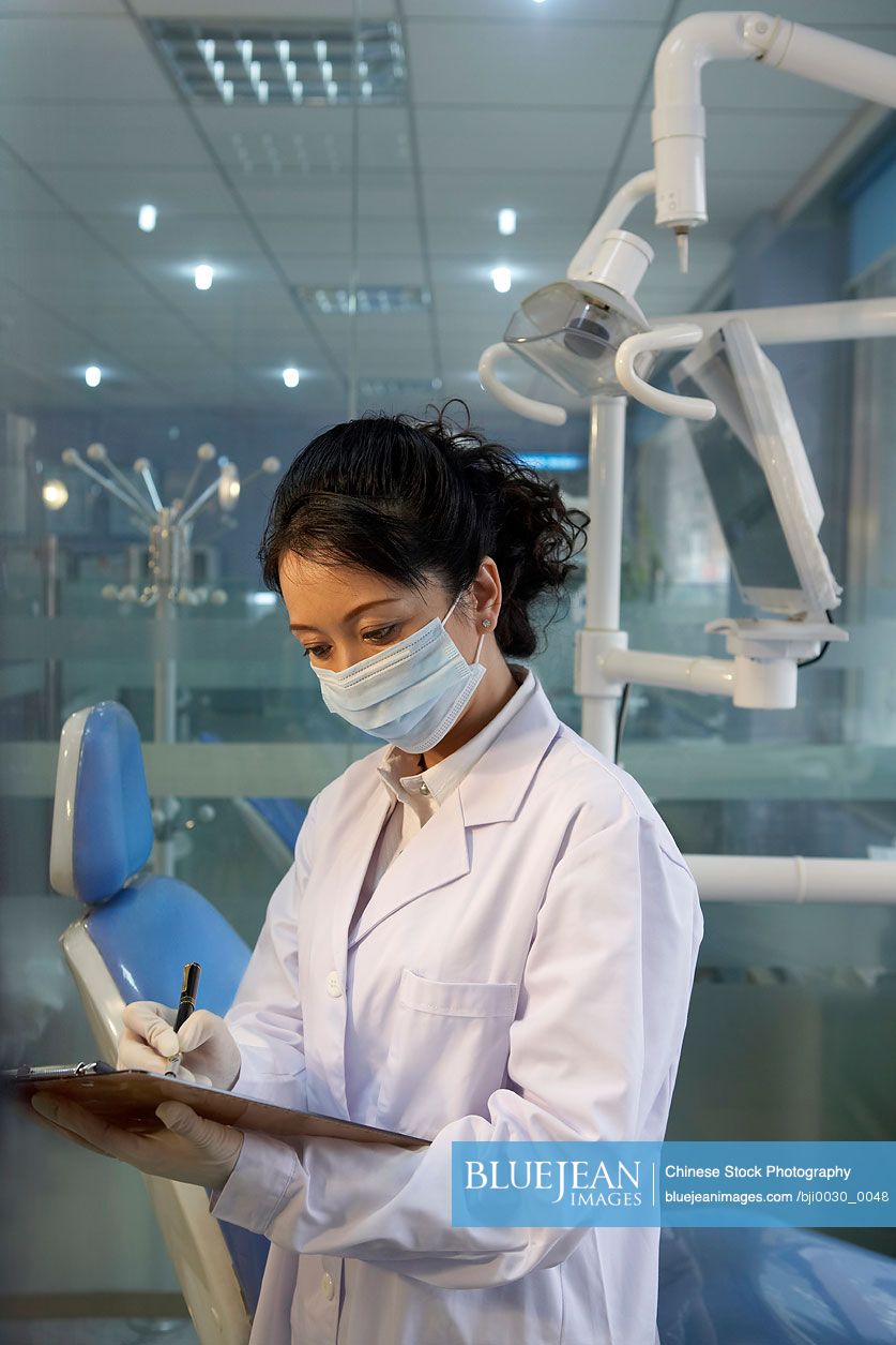 Chinese dentist writing on clipboard