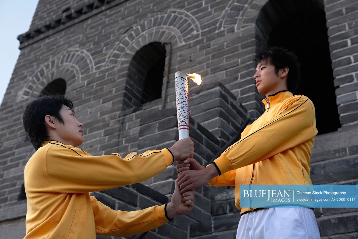 One young Chinese man passing the torch to another Olympic torch at the UNESCO world heritage site