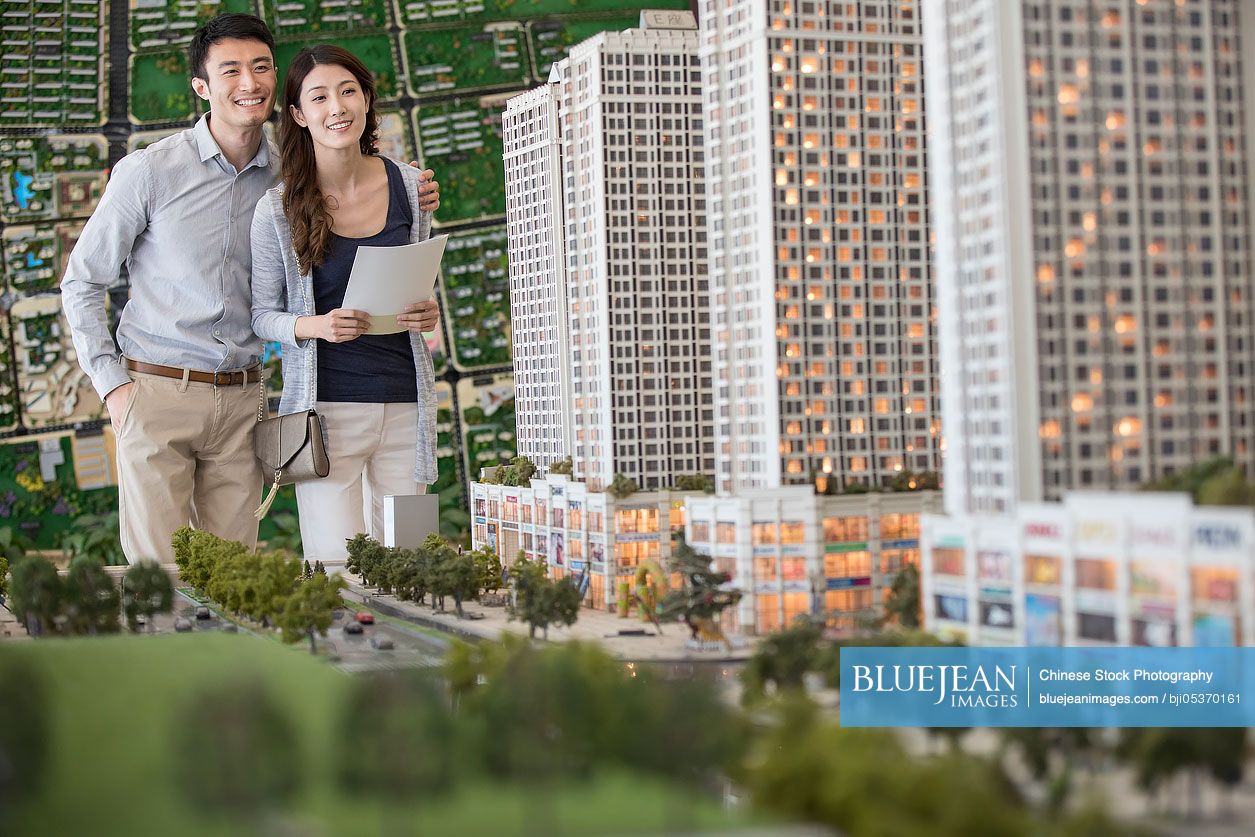 Happy young Chinese couple buying new house from sales center