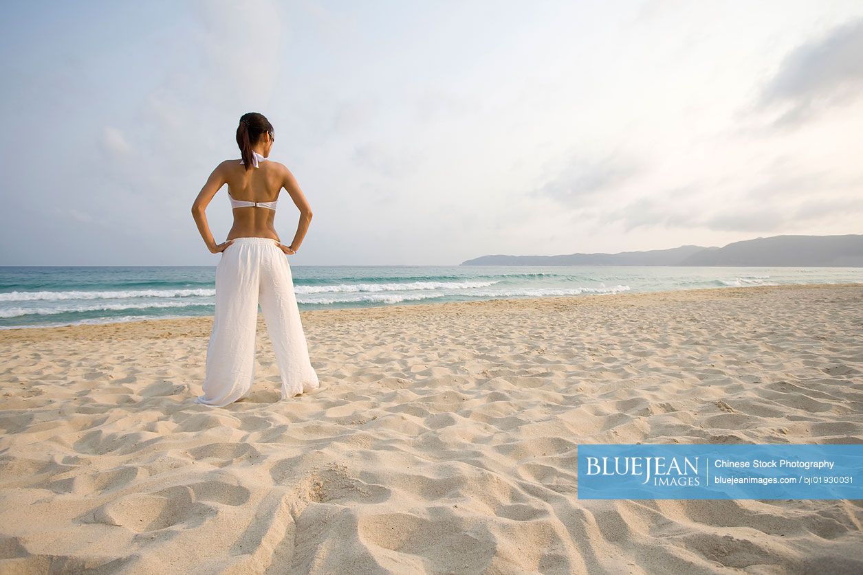 Young Chinese woman doing yoga on the beach