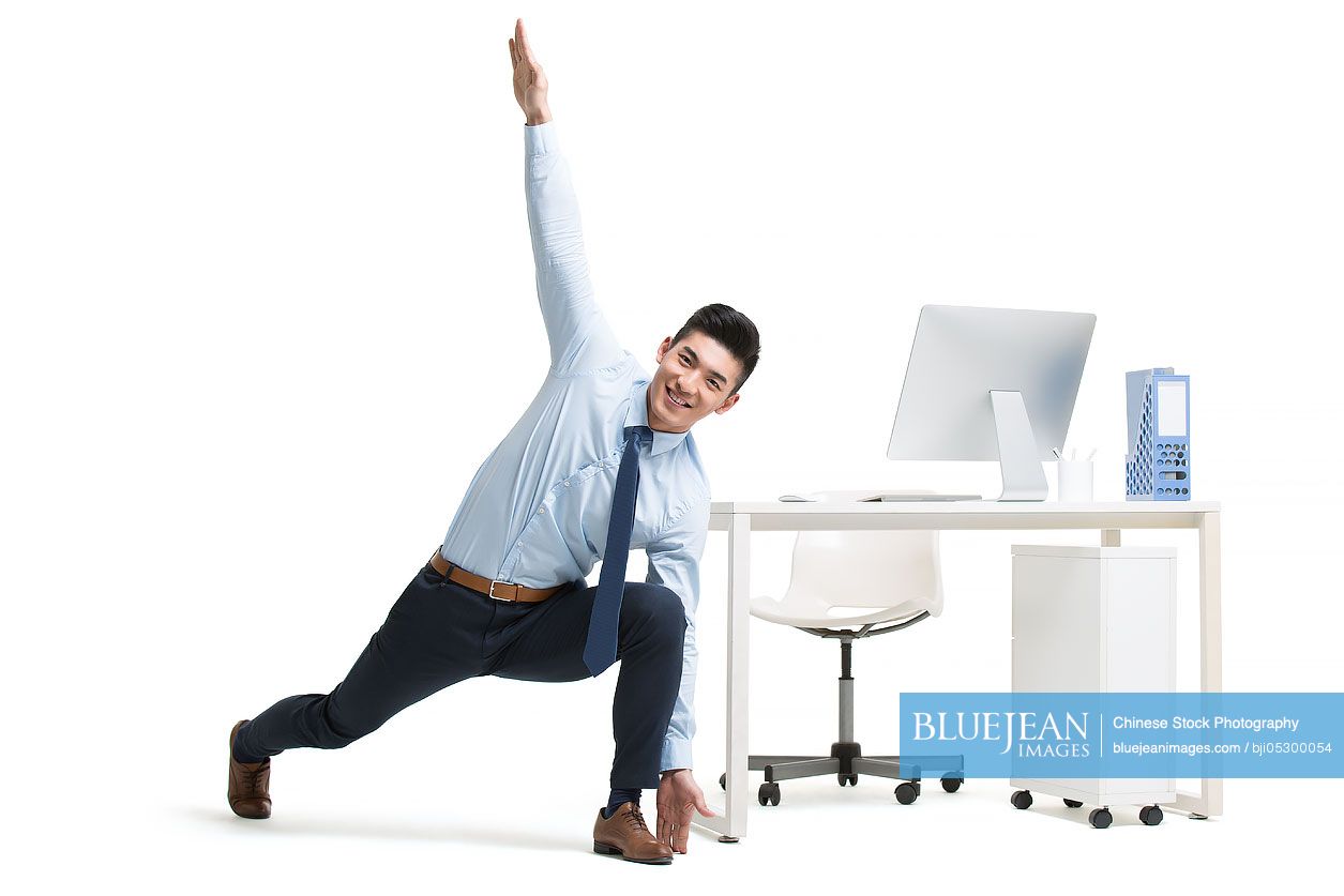 Young Chinese businessman exercising in office