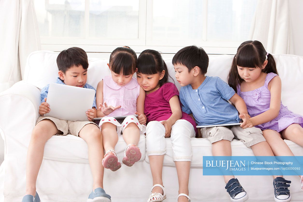 Chinese children playing digital tablet at home