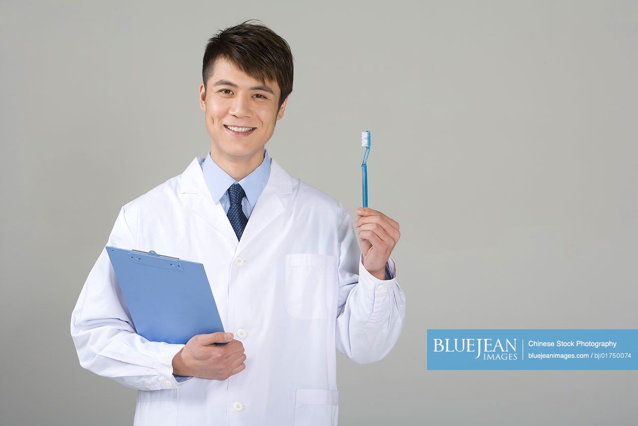 Young Chinese doctor holding a toothbrush