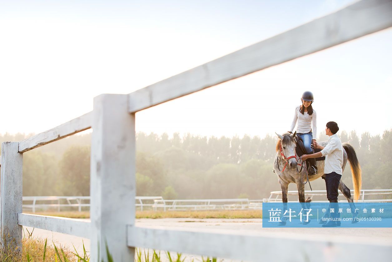 年轻情侣在马场骑马