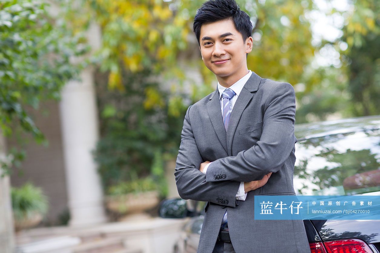 年轻商务男子倚车而站