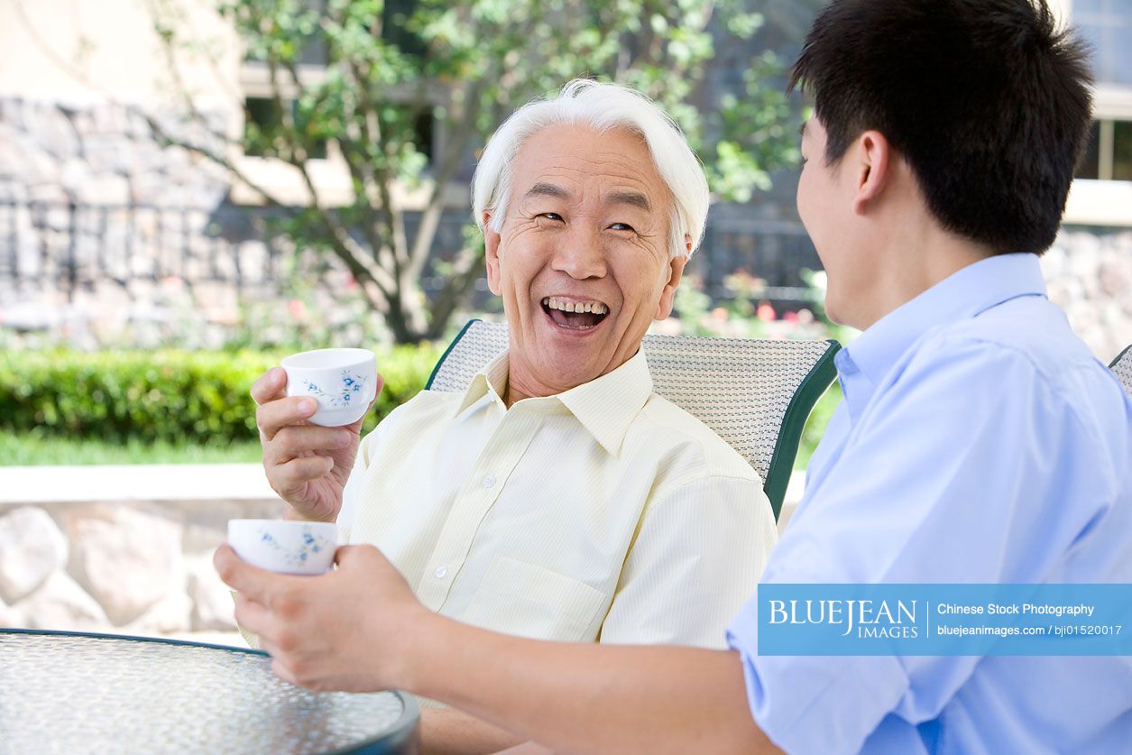 Chinese father and son chatting and having tea