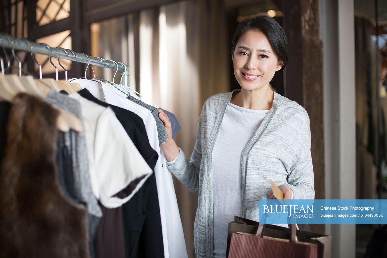 Mature Chinese woman with credit card in clothing store